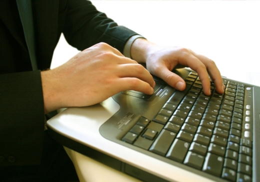 Egy férfi két keze gépel egy laptopon.