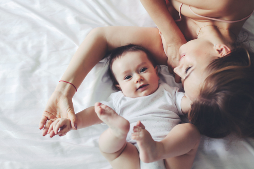 Egy anya játszik a négy hónapos kisbabájával az ágyban.