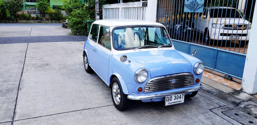 Egy kék Mini Cooper egy kapubejáró előtt parkol.