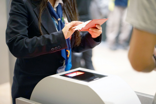 A repülőtéren a stewardess ellenőrzi a beszállókártyát és az utas útlevelét.