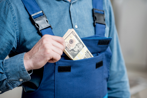 Egy munkásember a zsebébe csúsztat egy pénzköteget.